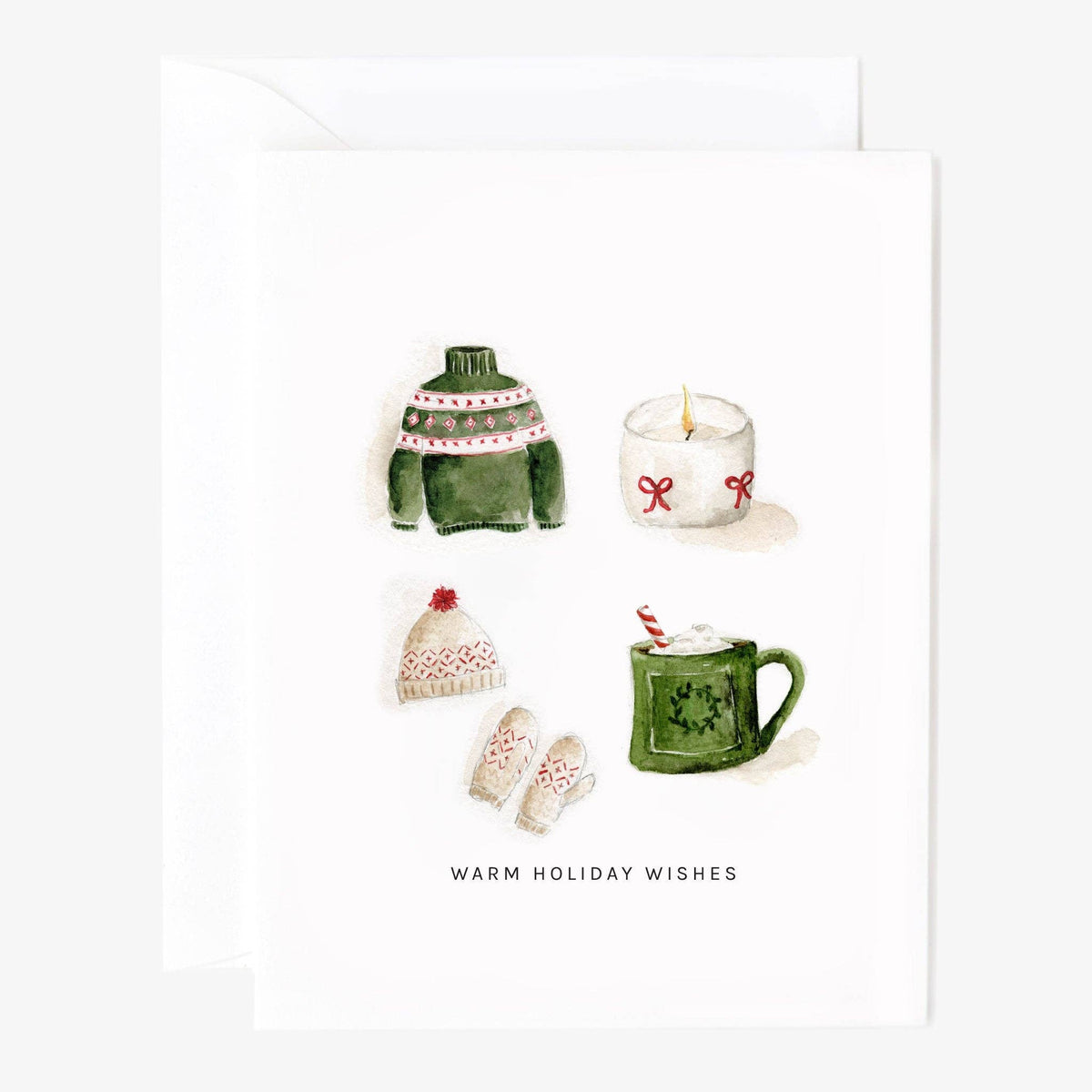 A white greeting card with a watercolor illustration of holiday items, including a green sweater, a white candle, a knit hat, mittens, and a green mug, with the text 'WARM HOLIDAY WISHES' below. A matching white envelope is partially visible behind the card.