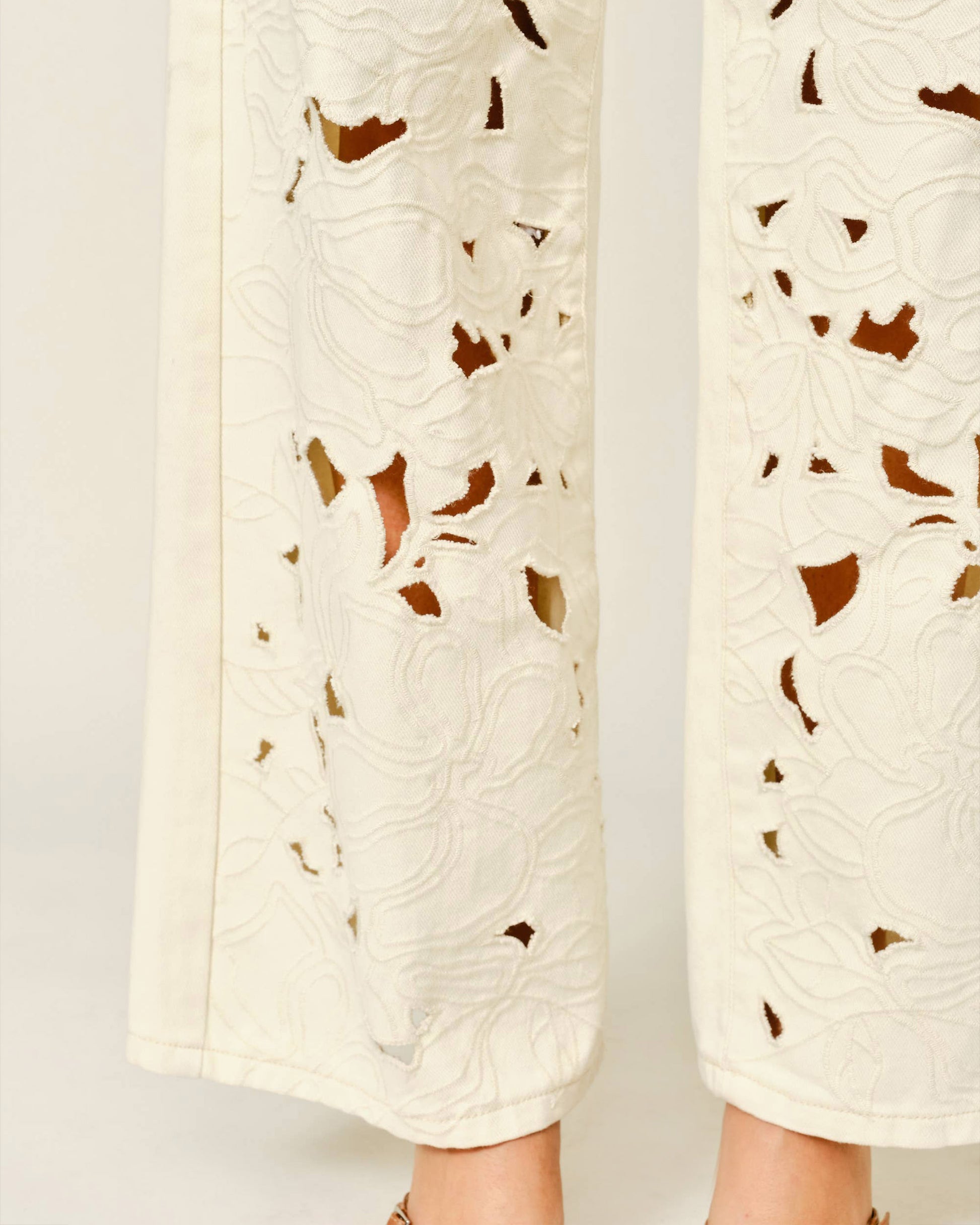 White pants with brown leaf patterns on a light gray background
