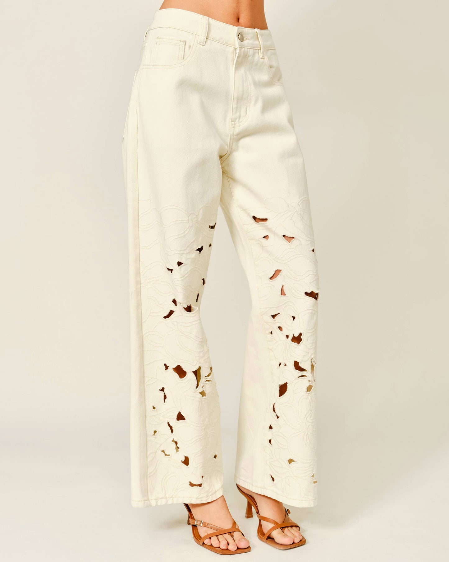 White pants with brown abstract patterns on a plain background