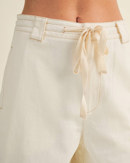 Beige pants with a tie detail on a plain background