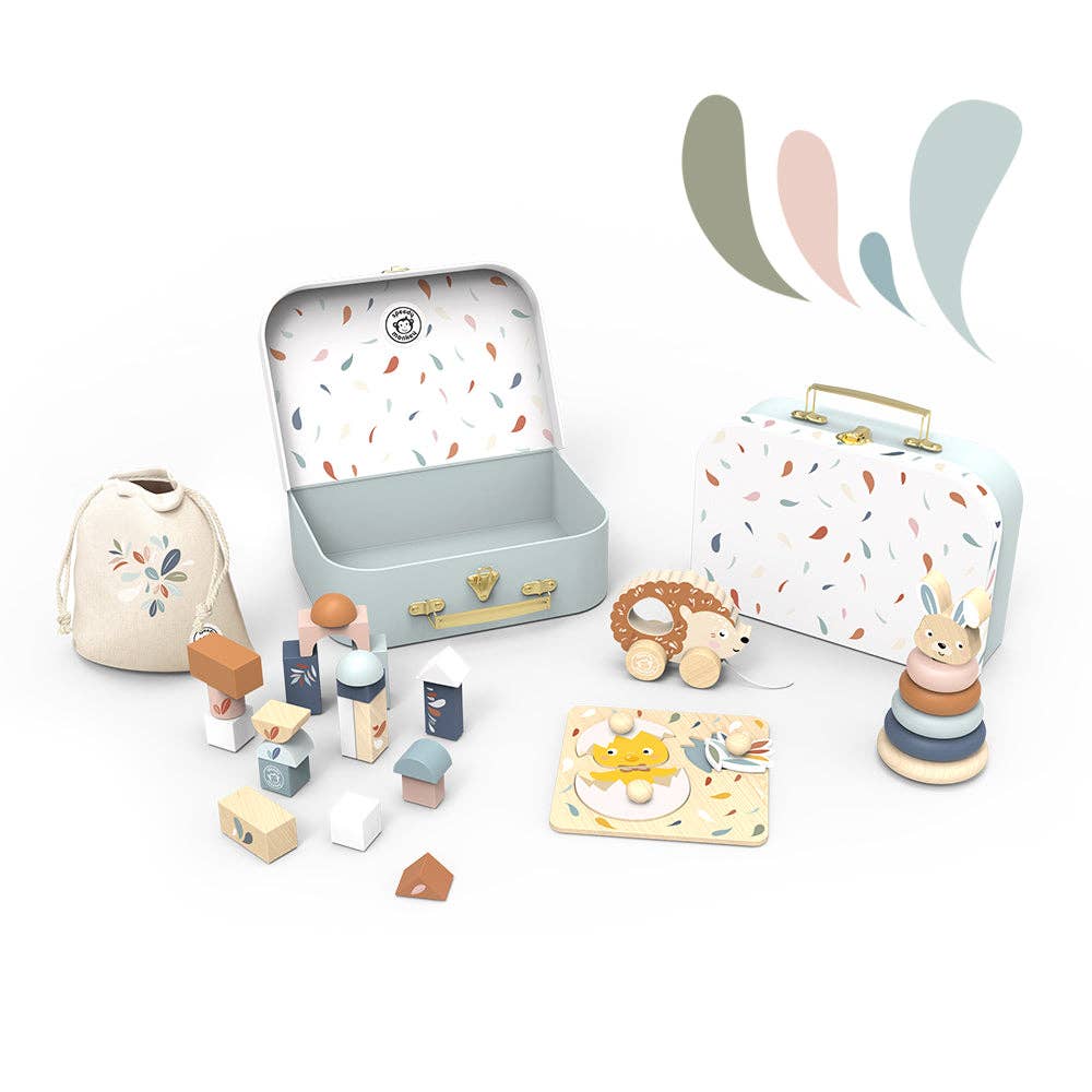 Collection of wooden toys including blocks and a rabbit figure, displayed with a colorful suitcase and small bag on a white background.