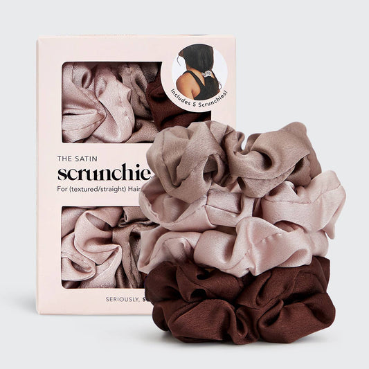 Three satin hair scrunchies in dusty pink, taupe, and dark brown are displayed in front of their light pink packaging box. The box features the brand name 'THE SATIN scrunchie' and a circular inset showing a model wearing a scrunchie.
