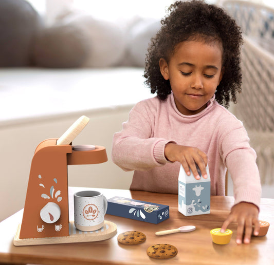 Child playing with a toy kitchen set on a table